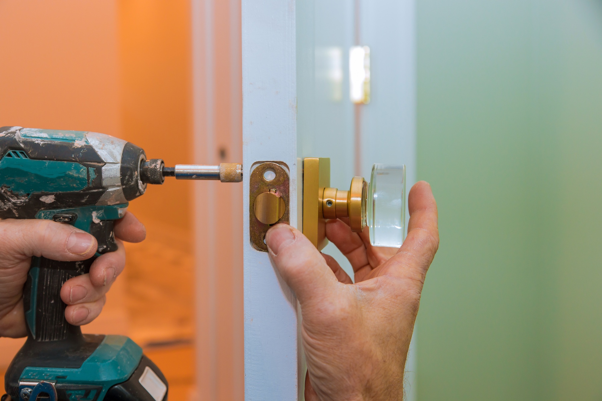 Closeup of a professional locksmith installing or new lock on a house door handle with screwdriver