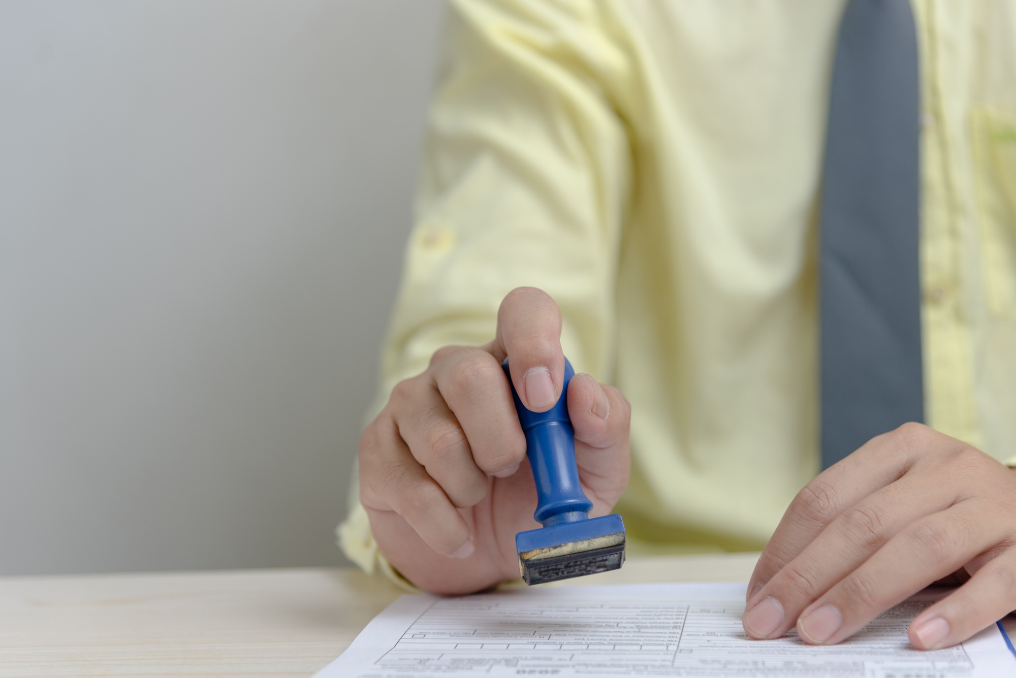 Man stamping approval of work finance banking or investment marketing documents on desk.